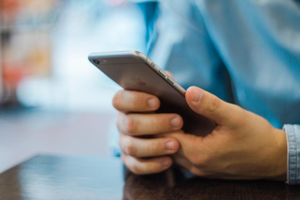 Hand holding a smartphone, ready to message a business